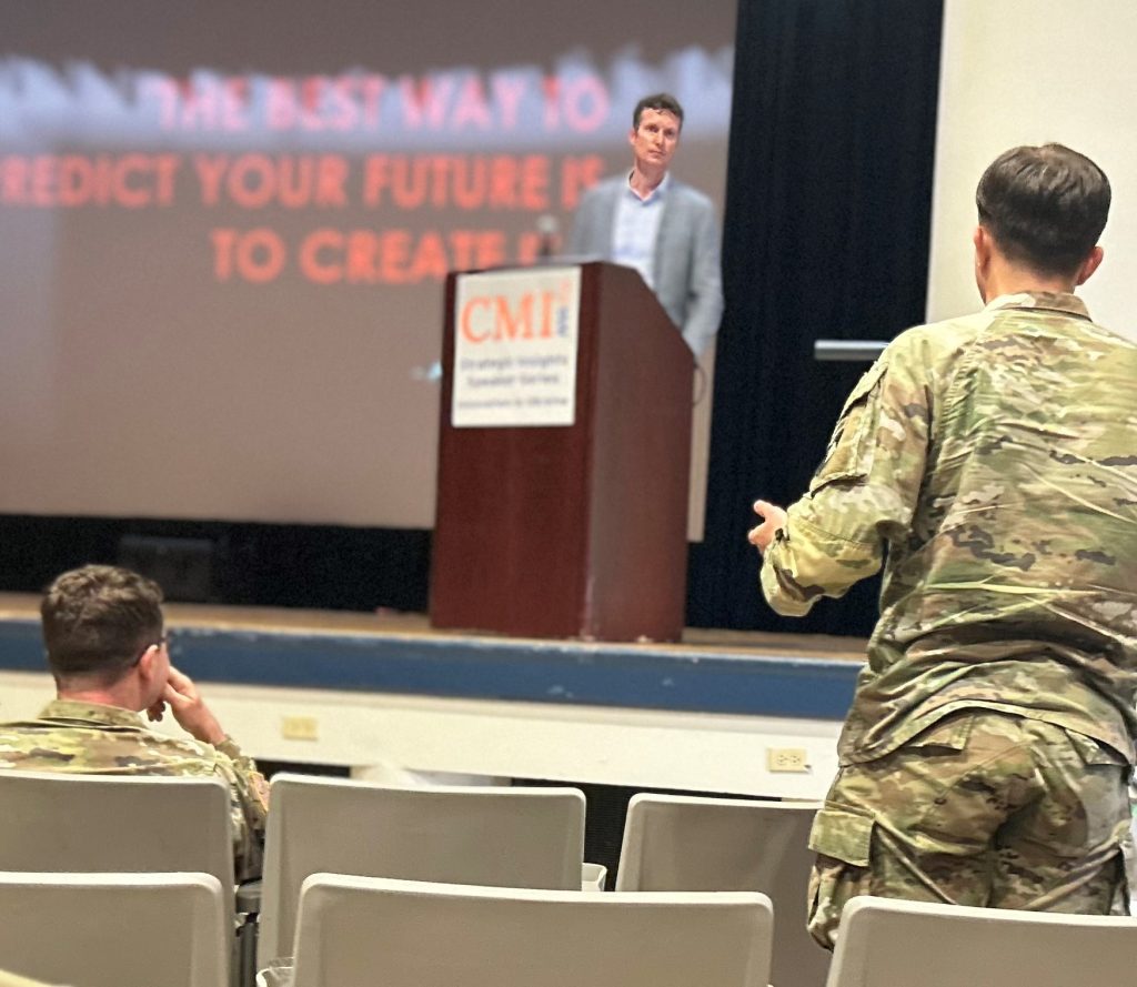 Soldier looks to man at podium during event