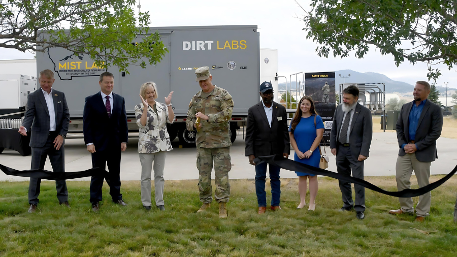 A man in uniform cuts a ribbon surrounded by other individuals. 